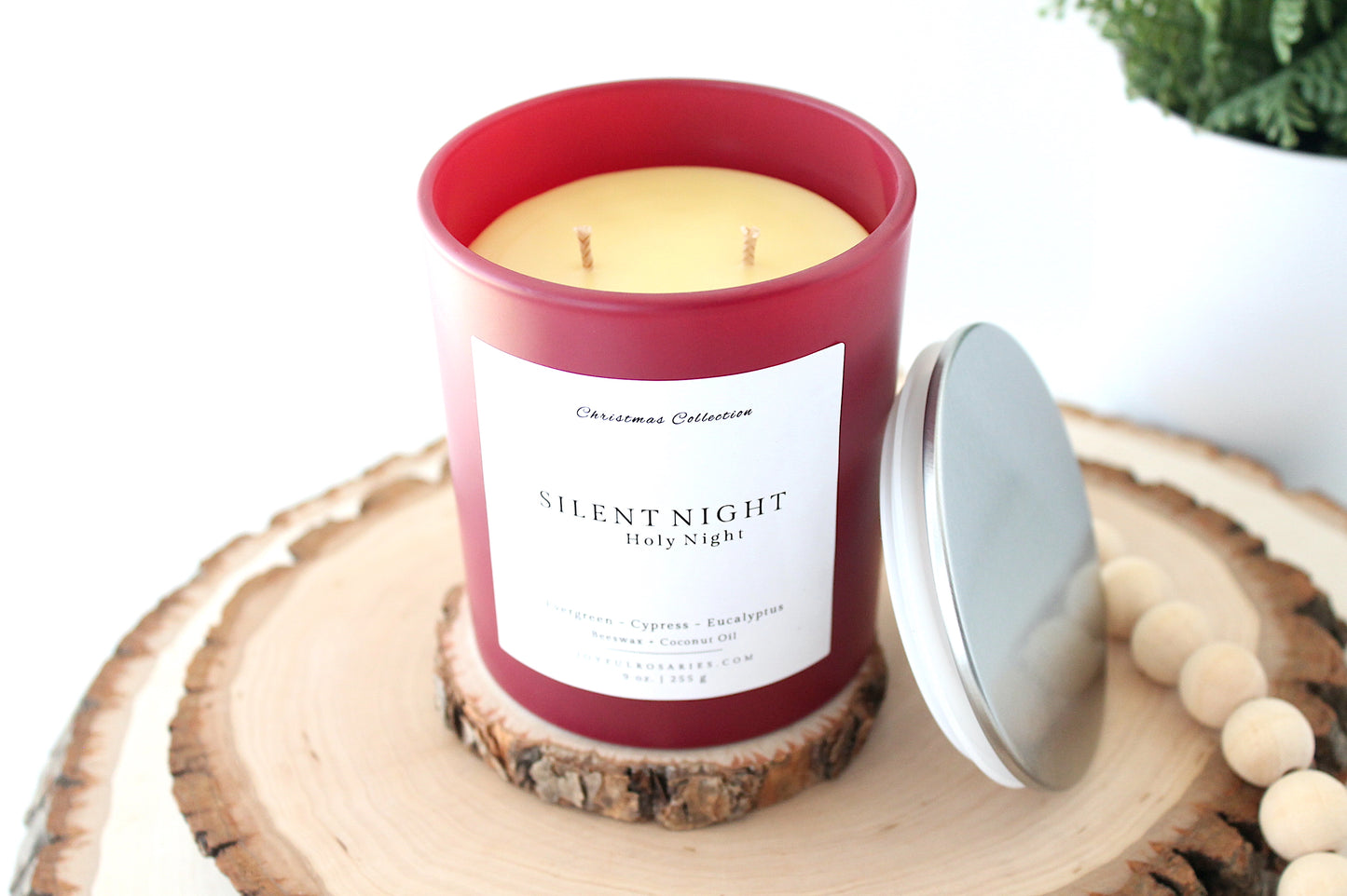 Candle in a red container labeled 'Silent Night' on a wooden surface with a white background