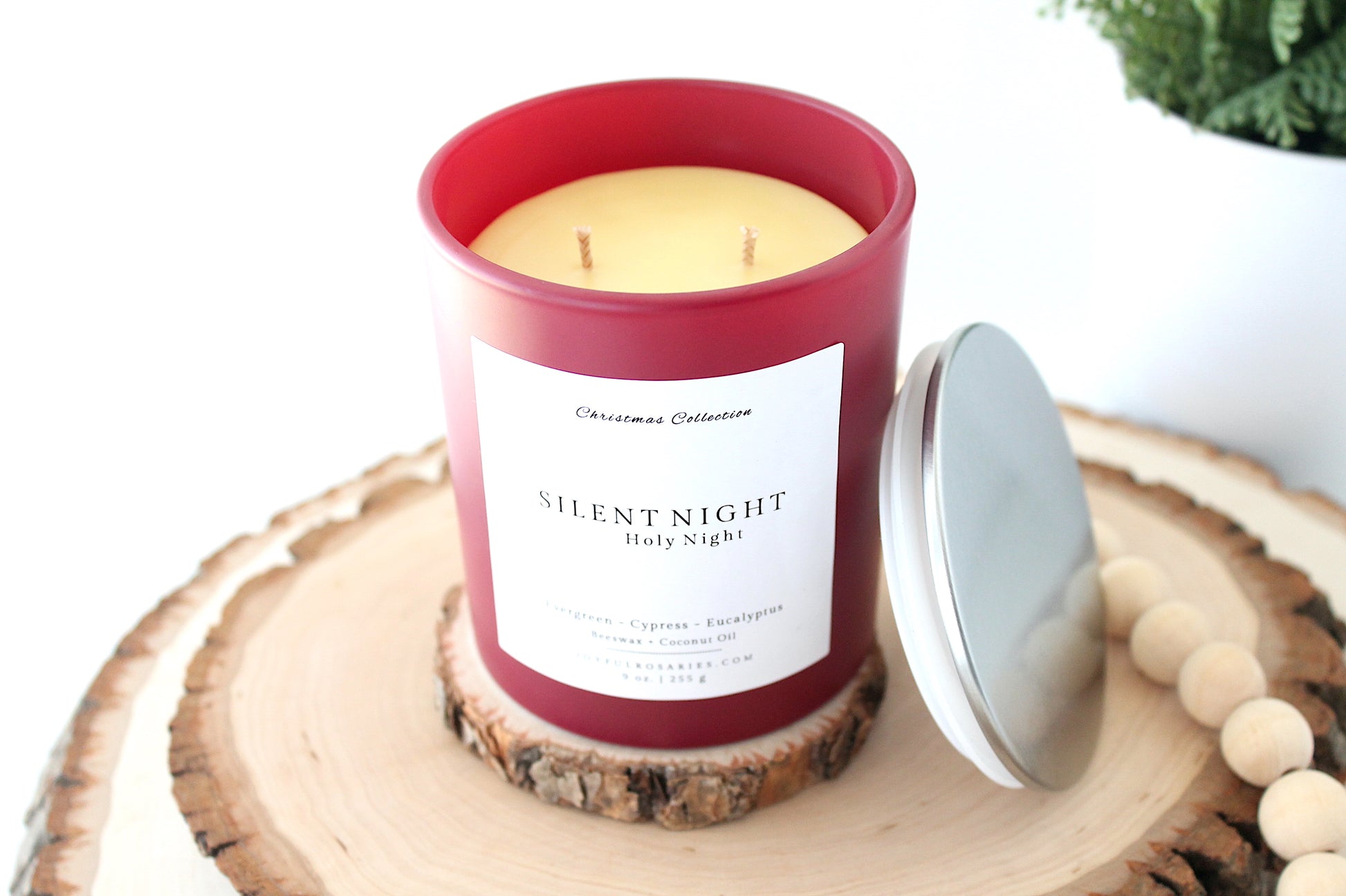 Candle in a red container labeled 'Silent Night' on a wooden surface with a white background