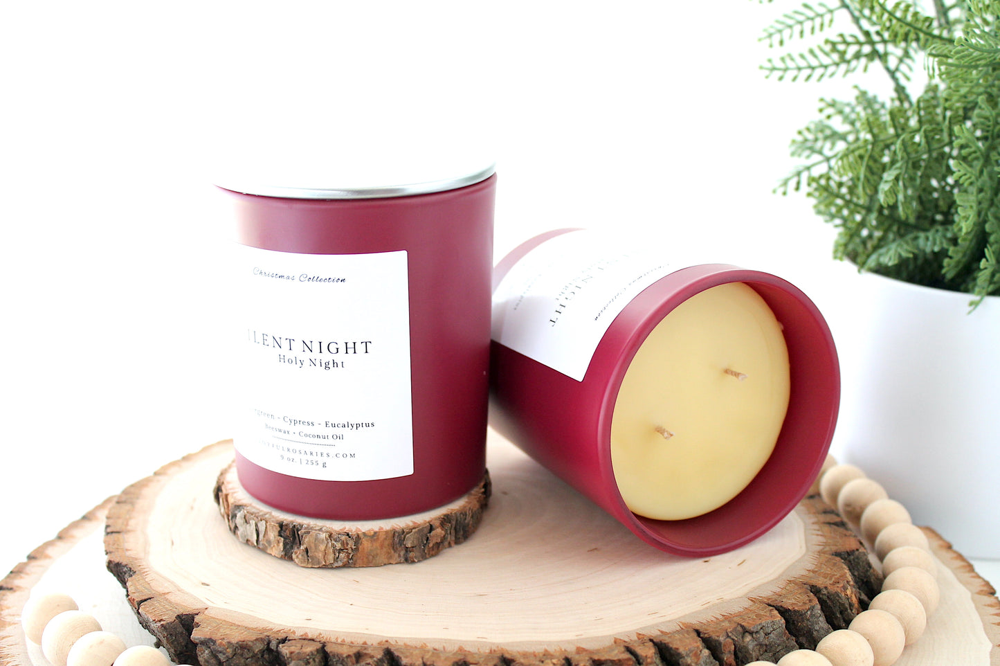 Two candles with red containers and white labels on a wooden surface.