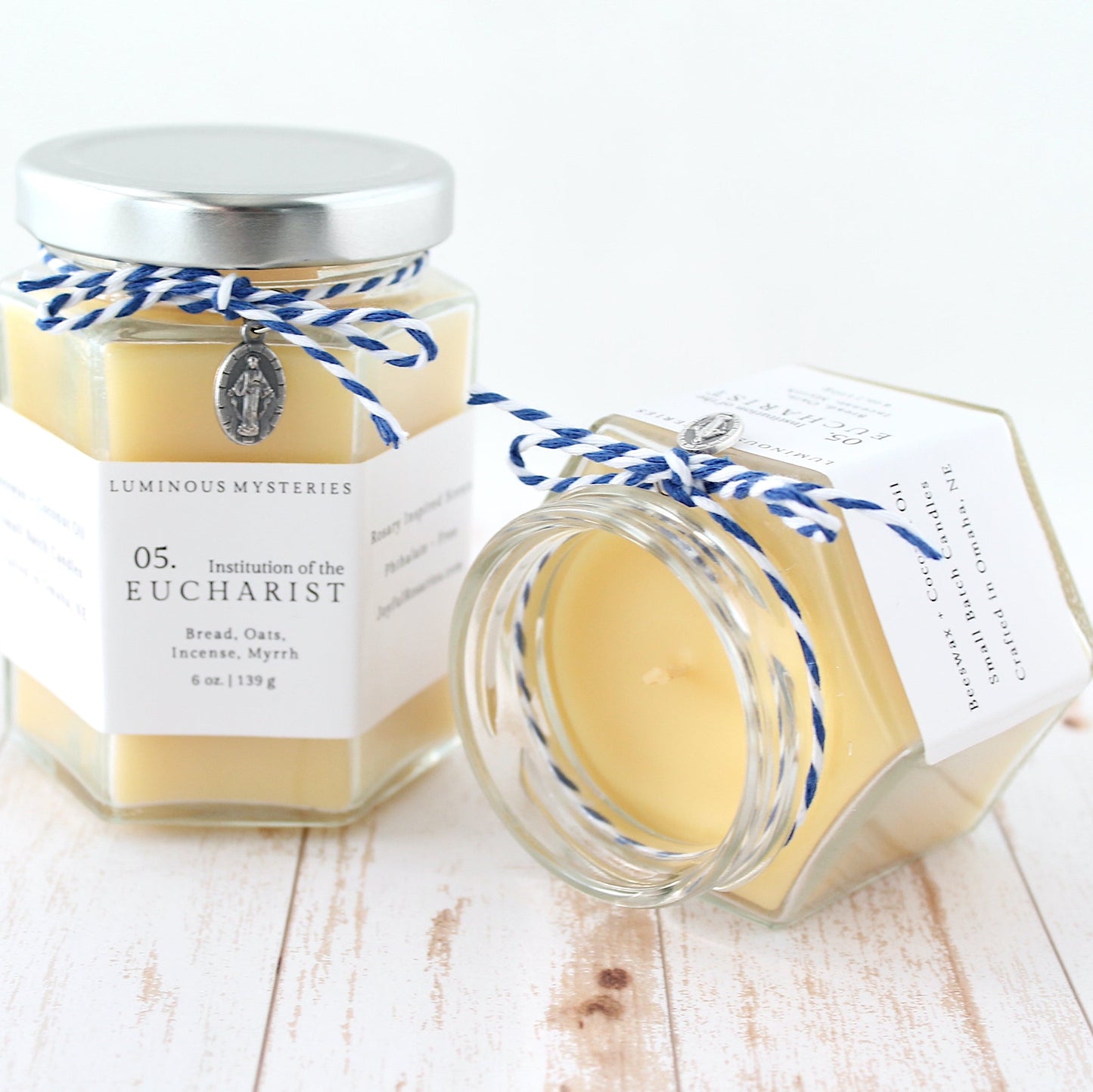 Two jars of Luminous Mysteries Eucharist on a wooden surface