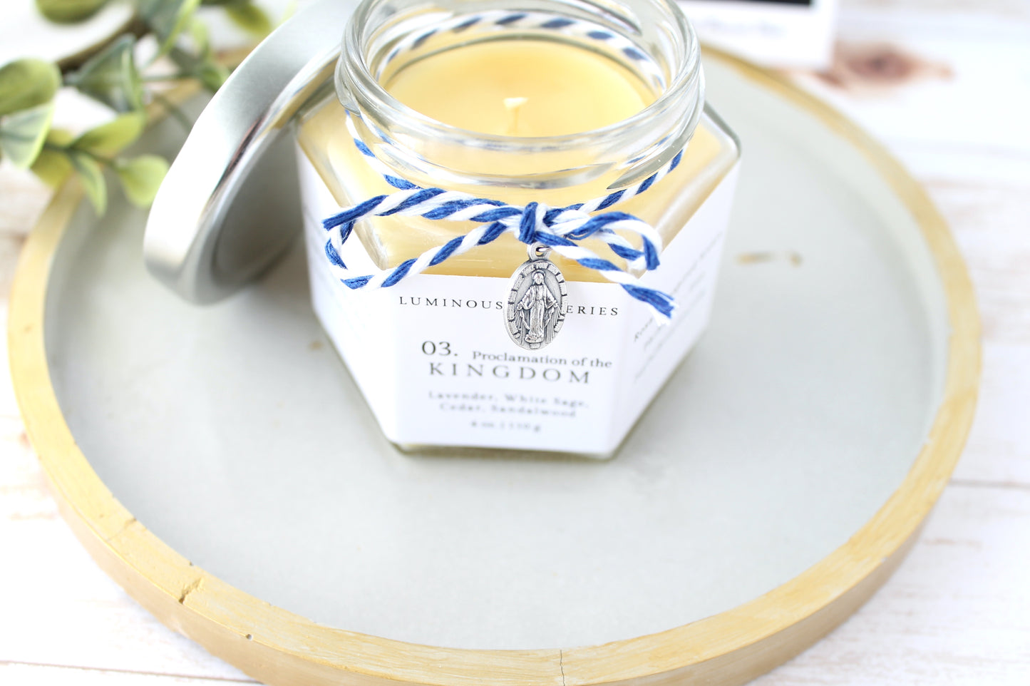 Jar of candle with decorative label on a white surface