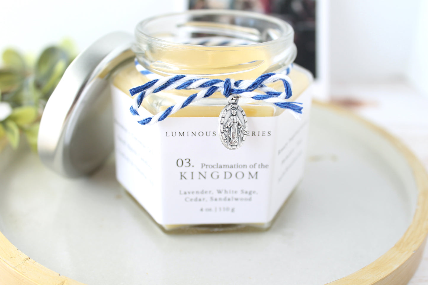 Jar of 'proclamation of the kingdom' candle with decorative elements on a light surface