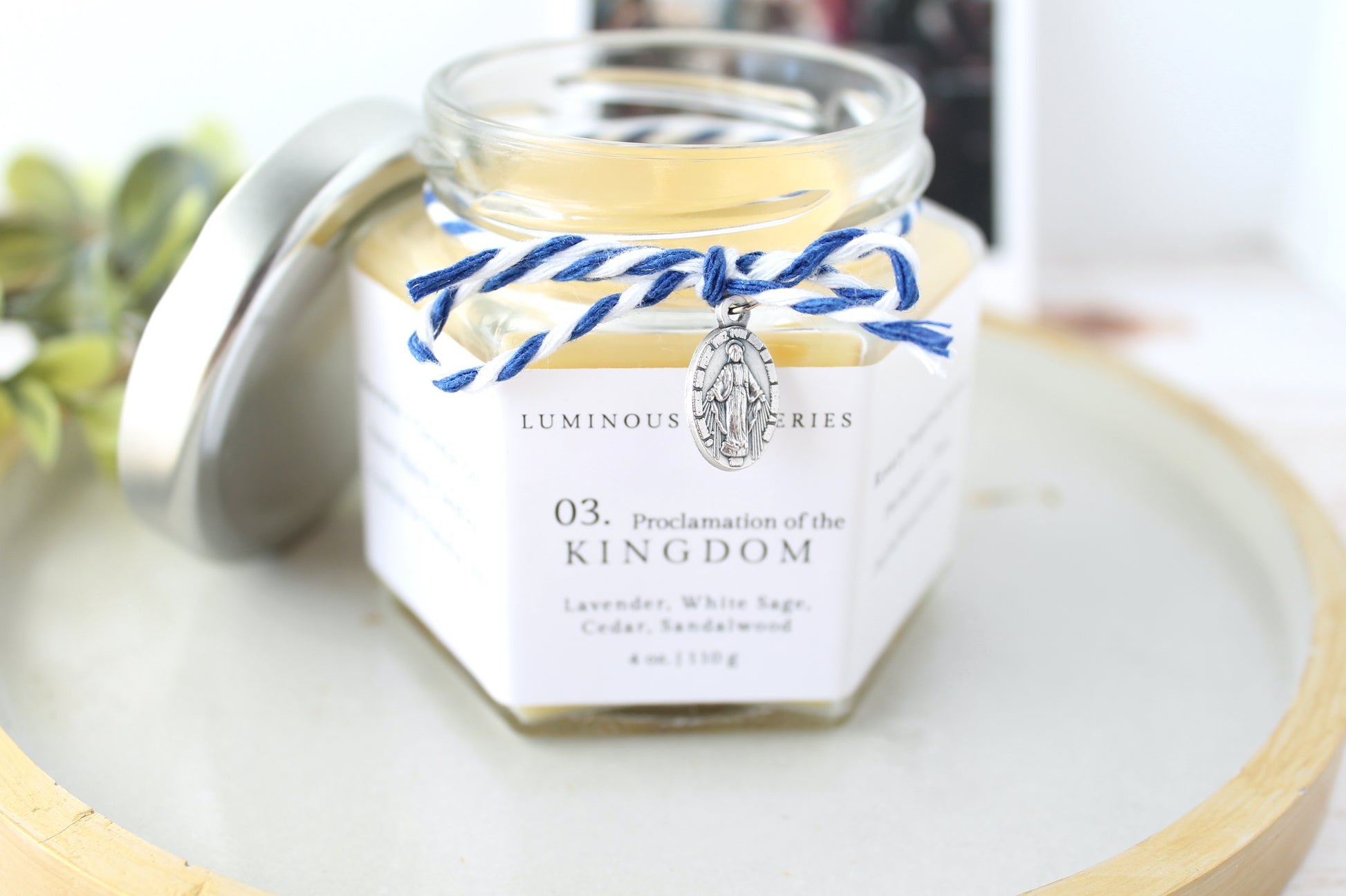 Jar of 'proclamation of the kingdom' candle with decorative elements on a light surface