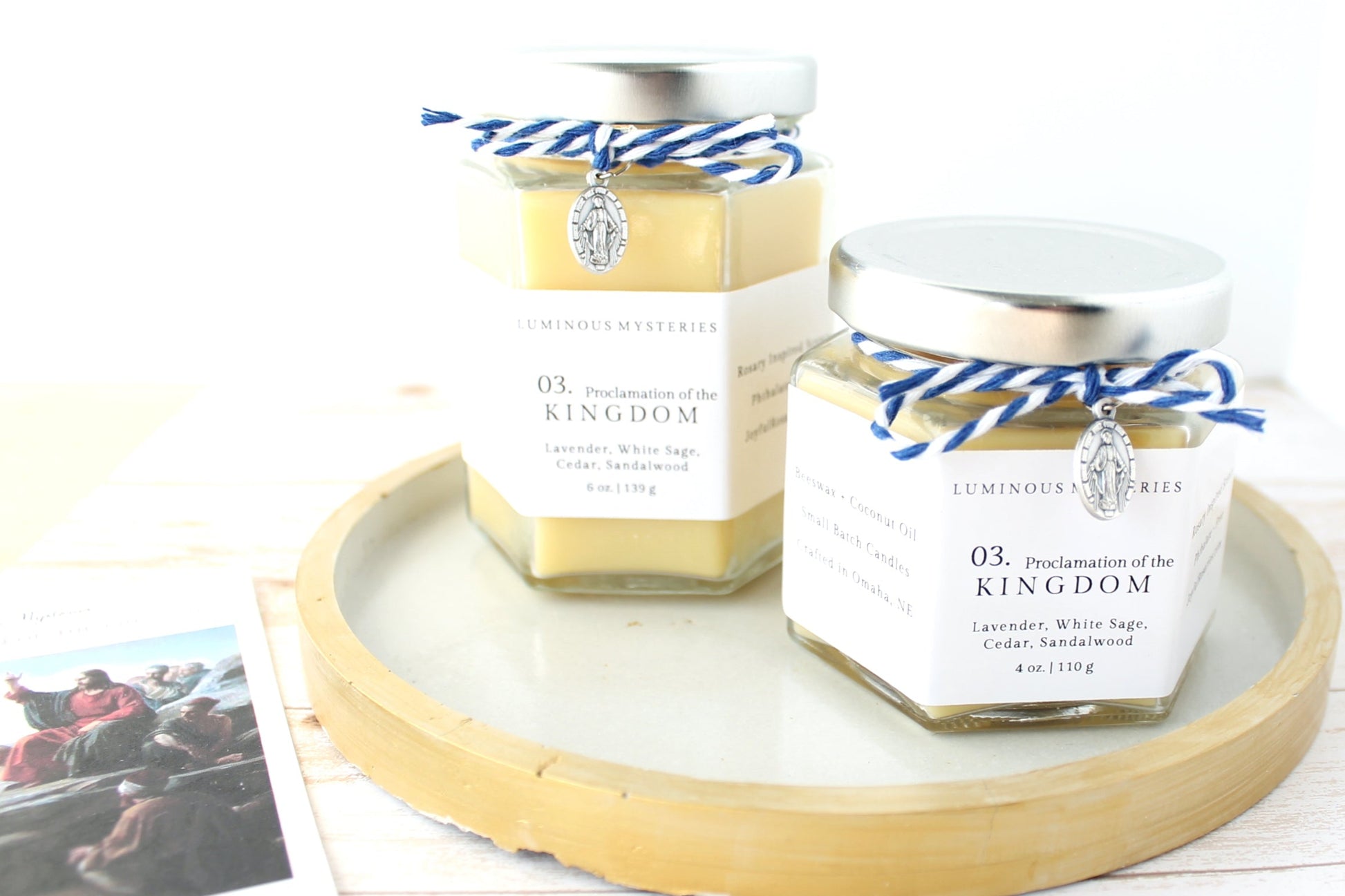 Two 'proclamation of the kingdom' candle jars on a tray with a holy card in the background