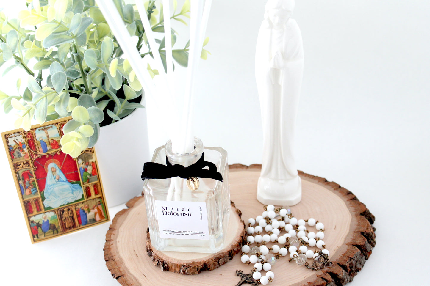 Decorative setup with a candle, cards, and plants on a white surface