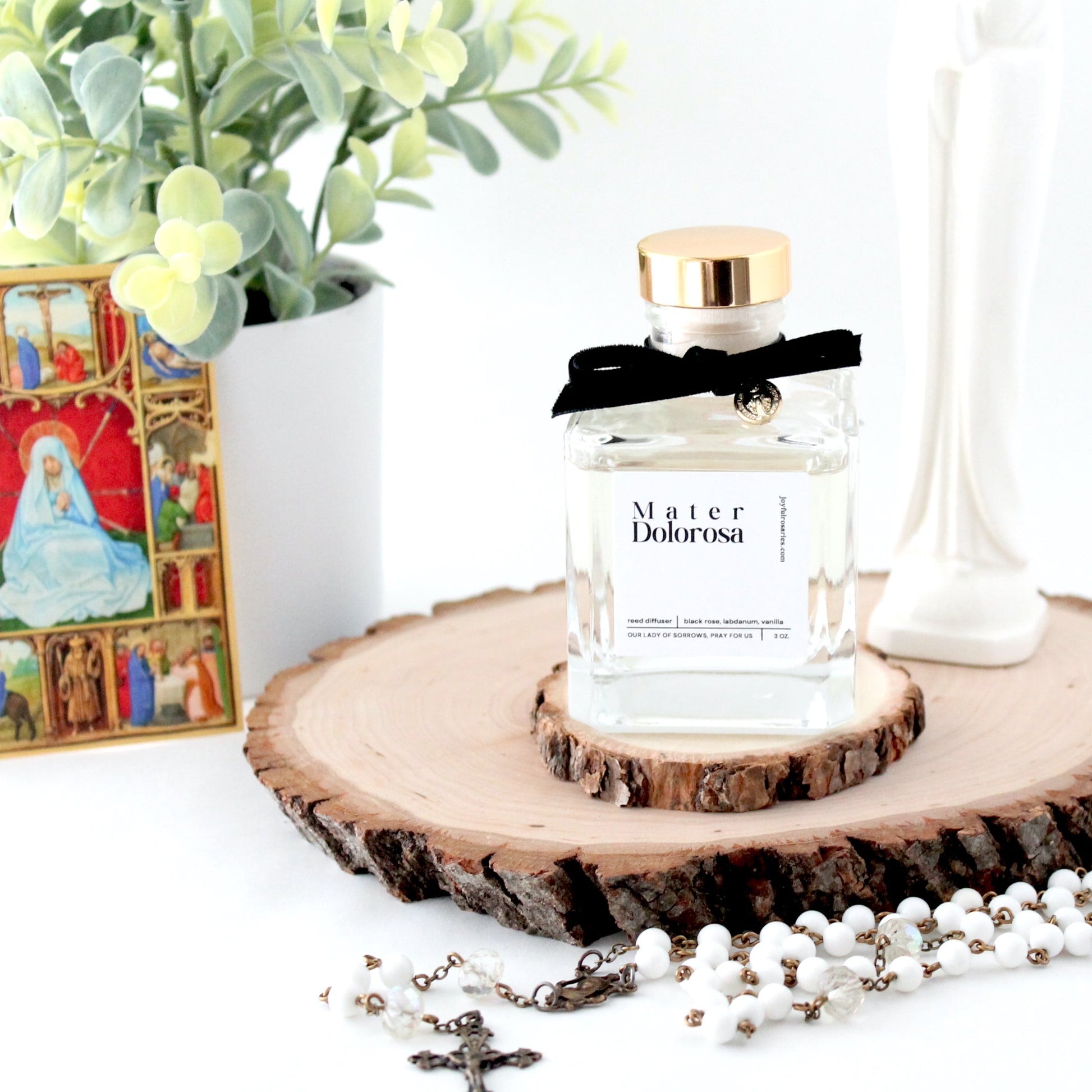 reed diffuser bottle with holy card and plant in the background