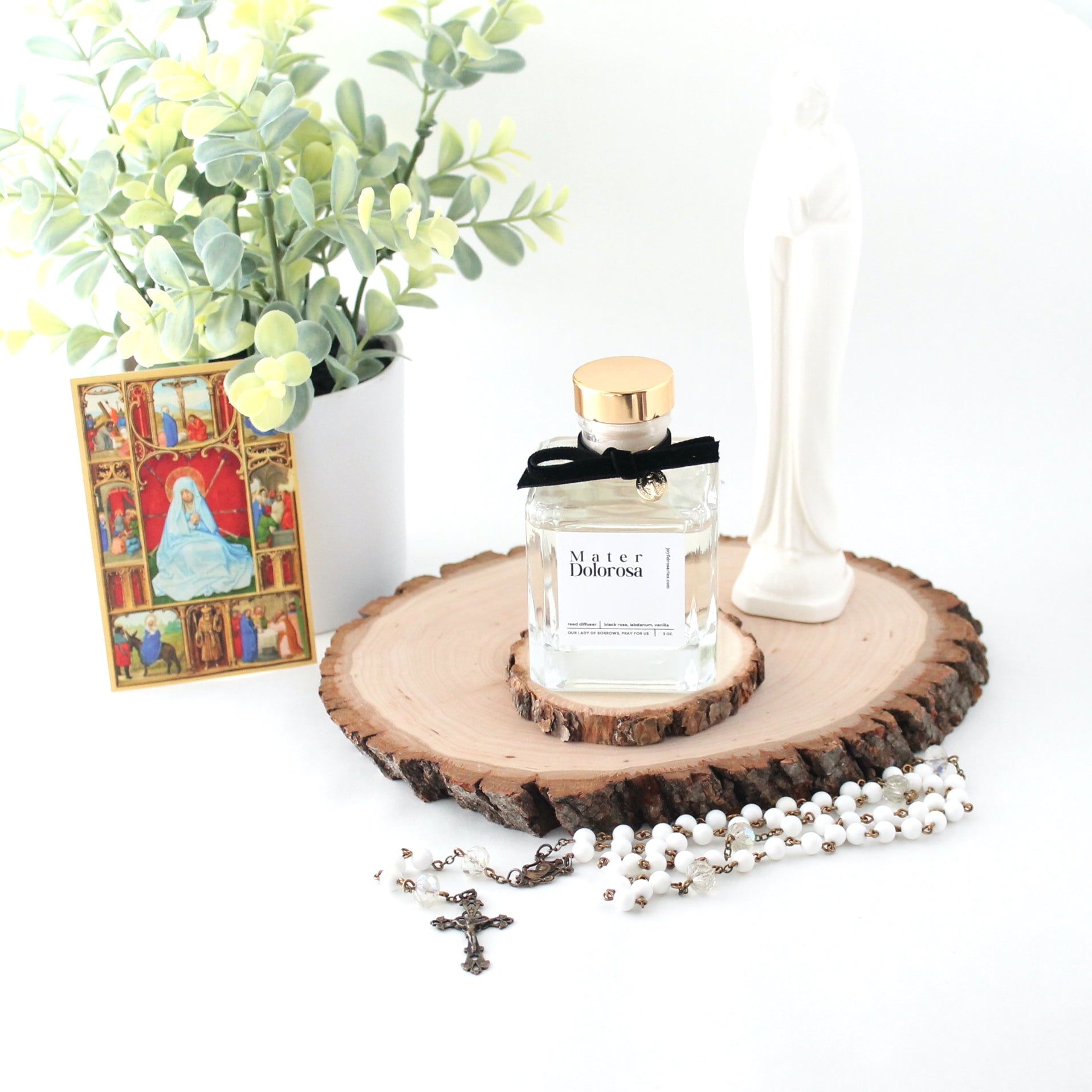 reed diffuser bottle with holy card and plant in the background