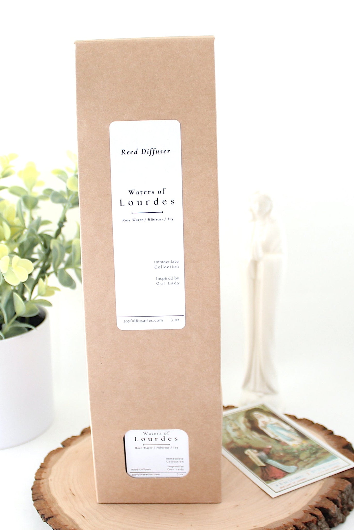 Product packaging on a wooden stand with a plant and Lourdes prayer card in the background