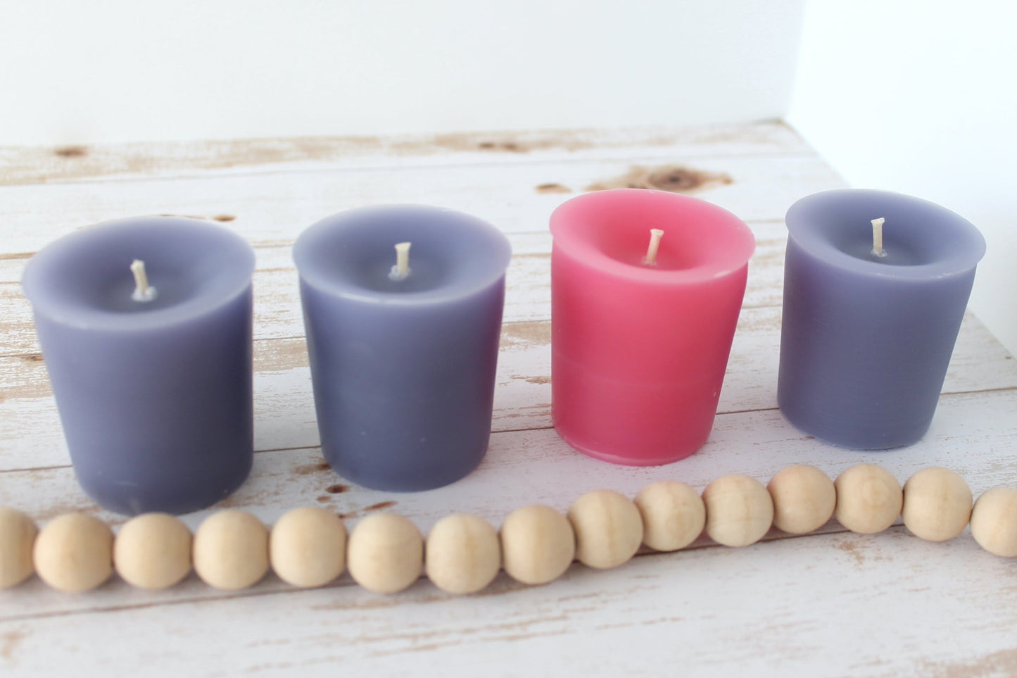 Four purple and pink candles against a white background